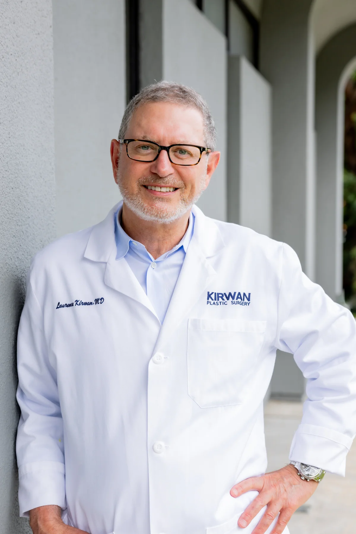Dr. Laurence Kirwan, MD, FRCS, FACS standing in a doorway in his white practice coat