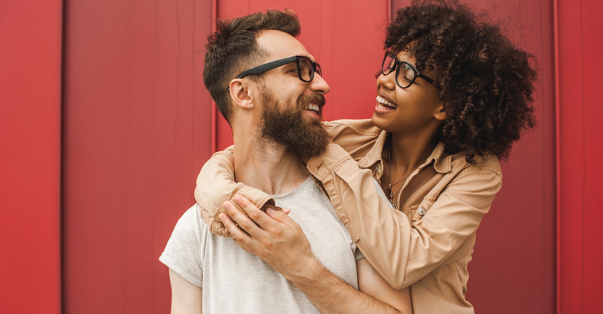 Happy young interracial couple in eyeglasses hugging and smiling each other